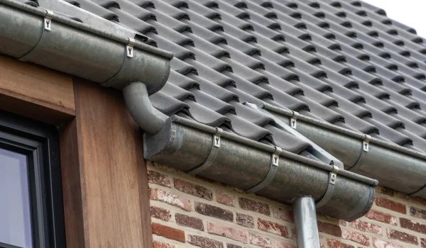 Zinken dakgoot en regenpijp op een pannendak